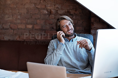 Buy stock photo Shot of a man talking on his cellphone while looking at his computer