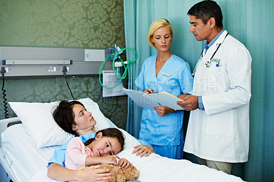 Buy stock photo Shot of doctors talking to a woman lying in a hospital bed with her daughter