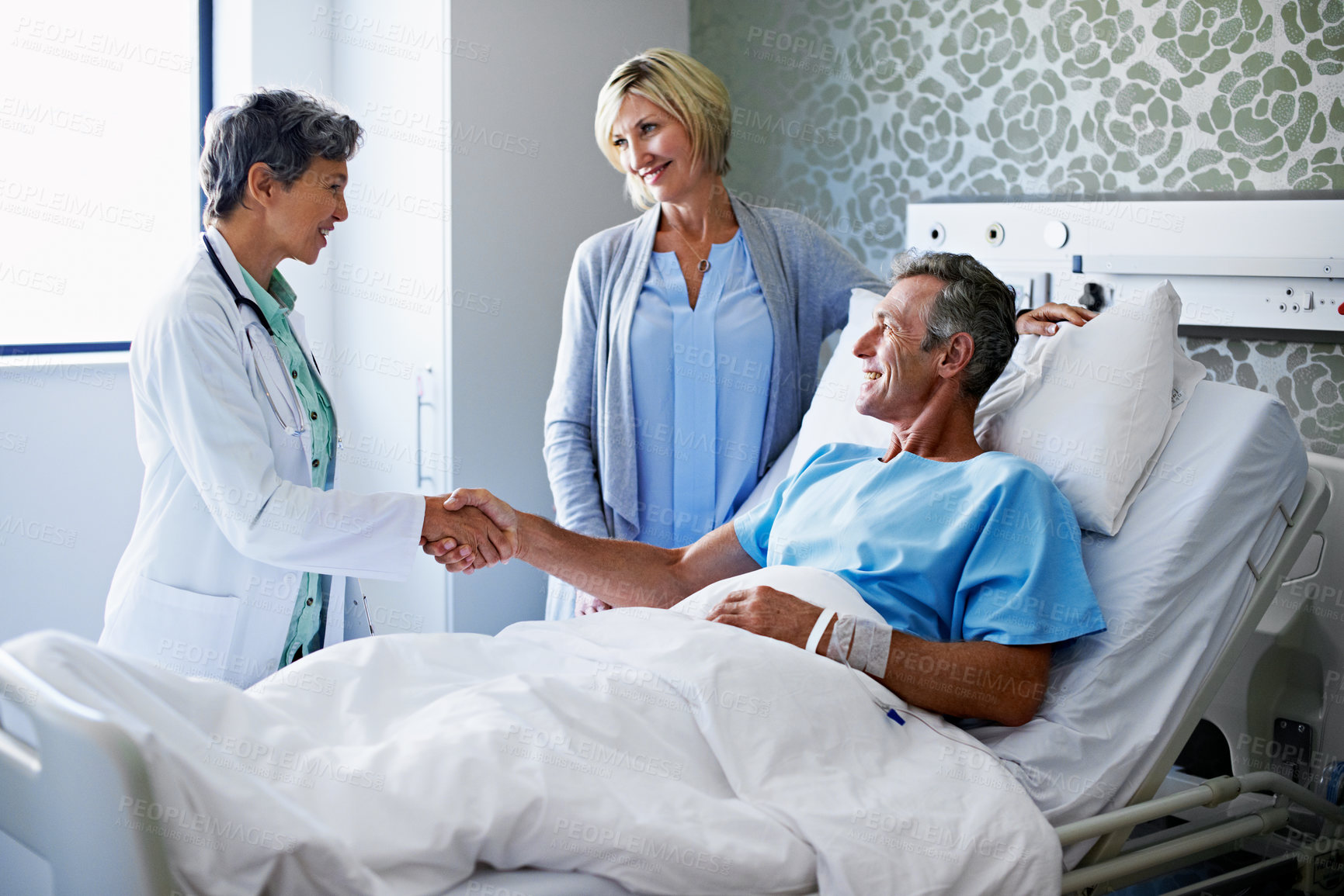 Buy stock photo Doctor, woman and handshake with couple in hospital bed for medical treatment or recovery. Mature, man and healthcare worker shaking hands with smile for good news, progress or thank you in clinic