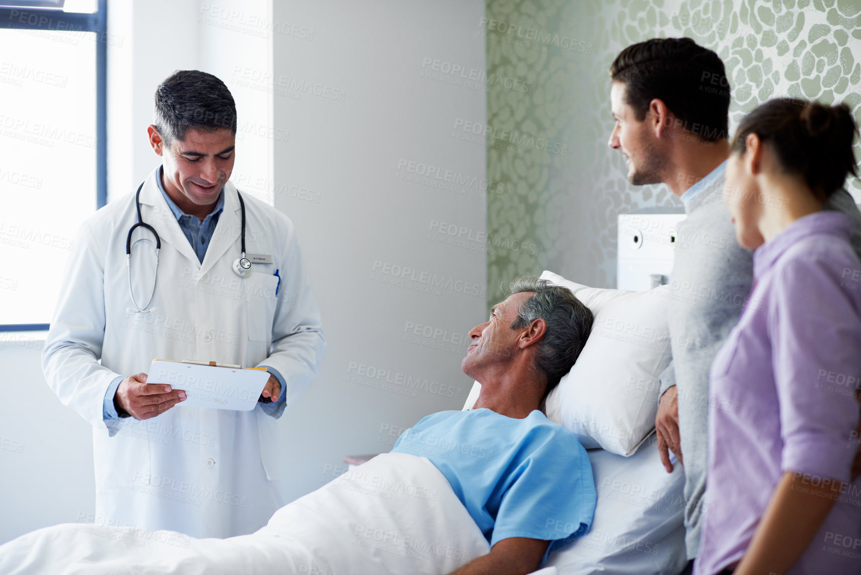 Buy stock photo Happy man, family and doctor at hospital bed with clipboard, test results or clear pathology report. Smile, patient and worker with medical records for discharge news, recovery and relatives support