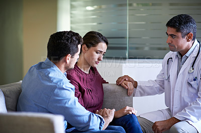Buy stock photo Shot of a doctor talking to a grieving woman and her husband in a hospital waiting room