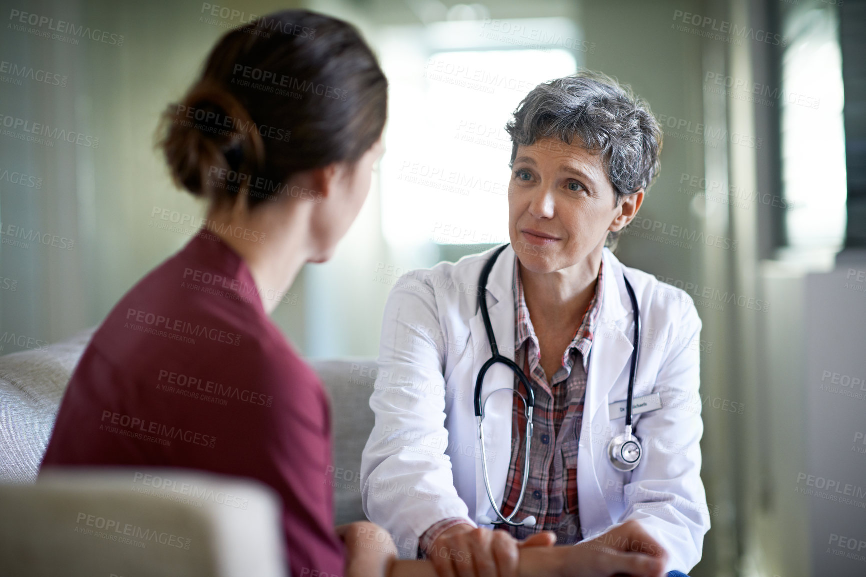 Buy stock photo Shot of a compassionate doctor comforting a young woman in a hospital waiting room