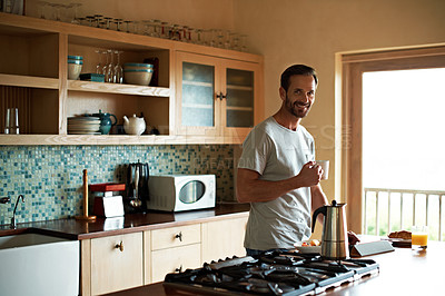 Buy stock photo Shot of a man using his digital tablet while eating breakfast at home