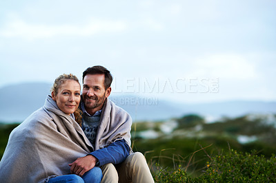 Buy stock photo Cropped shot of an affectionate couple wrapped in a blanket while sitting outdoors