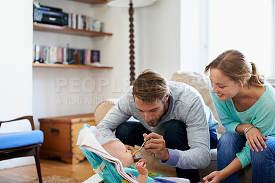 Buy stock photo Shot of a young couple feeding their baby at home
