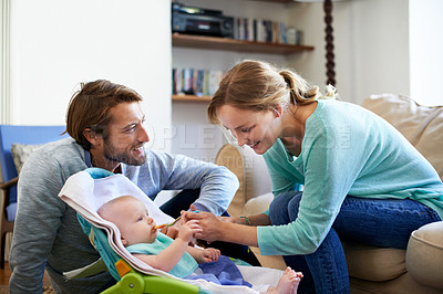 Buy stock photo Shot of a young couple feeding their baby at home