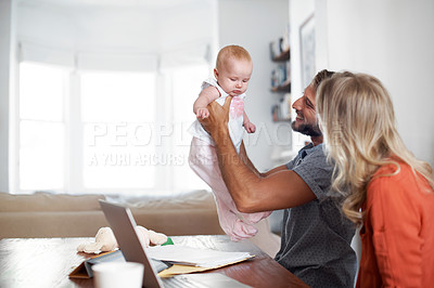 Buy stock photo Shot of a couple using a laptop while cradling their baby