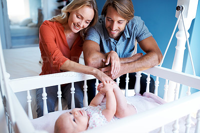 Buy stock photo Shot of a couple looking at their baby lying in a crib