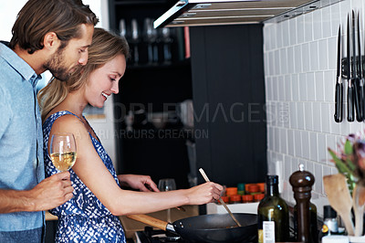 Buy stock photo Shot of a young couple cooking together in the kitchen