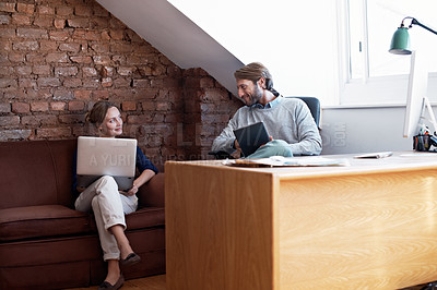 Buy stock photo Shot of a young couple using a digital tablet and laptop while relaxing at home