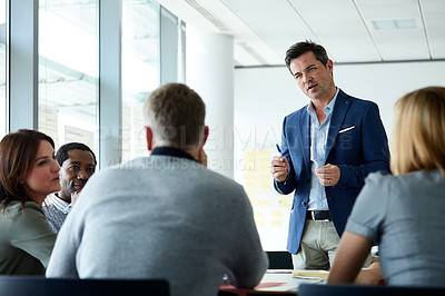 Buy stock photo Shot of a man giving a presentation to colleagues in an office
