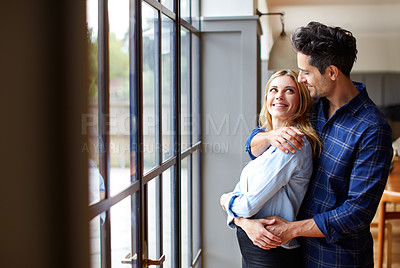 Buy stock photo Shot of a smiling young couple hugging each other in their kitchen