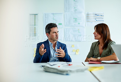 Buy stock photo Shot of two coworkers talking together while sitting in an office
