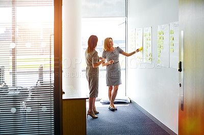 Buy stock photo Shot of two female colleagues talking together in a modern office