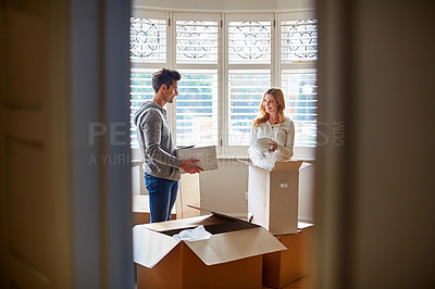 Buy stock photo Shot of a happy young couple unpacking boxes in their new house