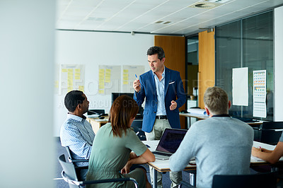Buy stock photo Shot of a man giving a presentation to colleagues in an office boardroom