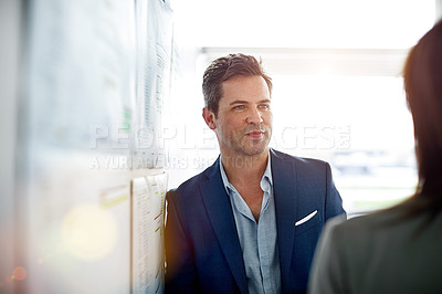 Buy stock photo Shot of two colleagues talking together in an office hallway