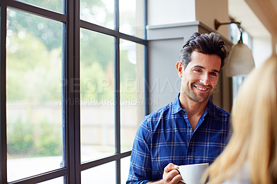 Buy stock photo Shot of a young couple drinking coffee together by a window in their kitchen