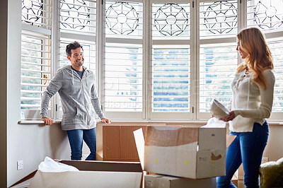 Buy stock photo Shot of a happy young couple unpacking boxes in their new house