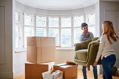 Buy stock photo Shot of a happy young couple carrying a chair in their new house