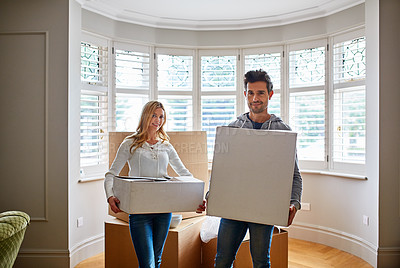 Buy stock photo Portrait of a happy young couple carrying boxes in their new house