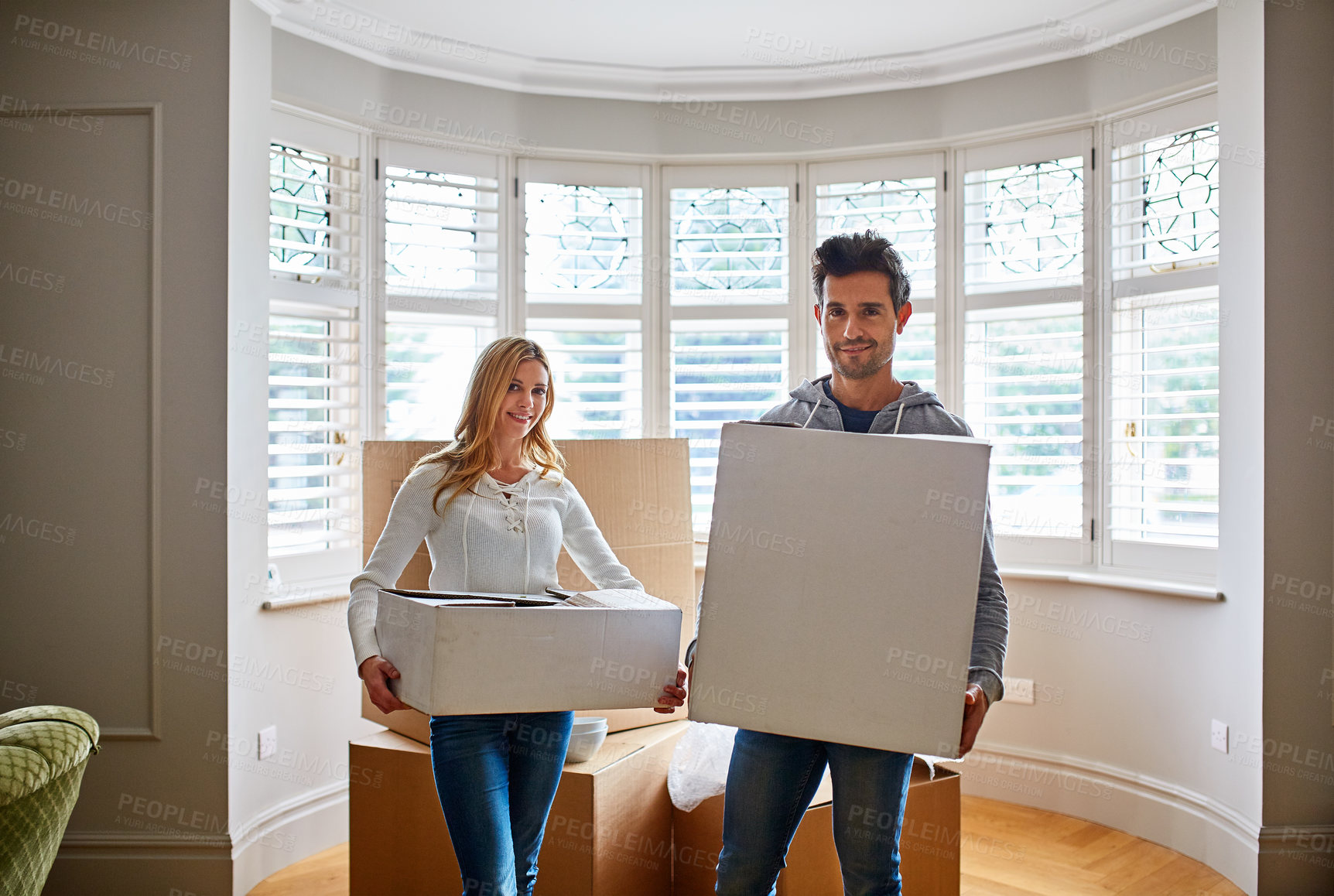 Buy stock photo Portrait of a happy young couple carrying boxes in their new house