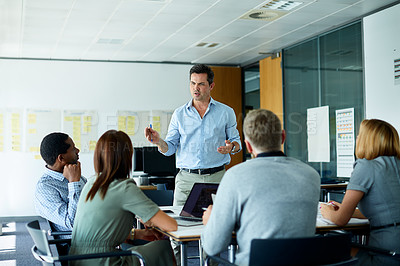 Buy stock photo Shot of a mature man addressing his colleagues in the office