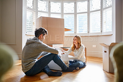 Buy stock photo Shot of a happy young couple unpacking boxes in their new house