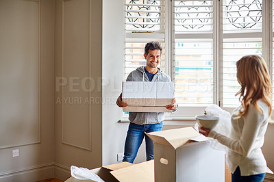 Buy stock photo Shot of a happy young couple unpacking boxes in their new house