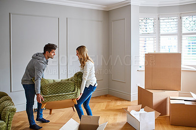Buy stock photo Shot of a happy young couple moving furniture in their new house