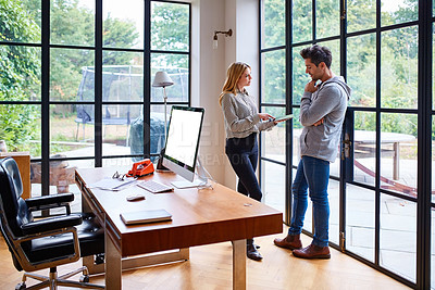 Buy stock photo Shot of a young couple working together in their home office