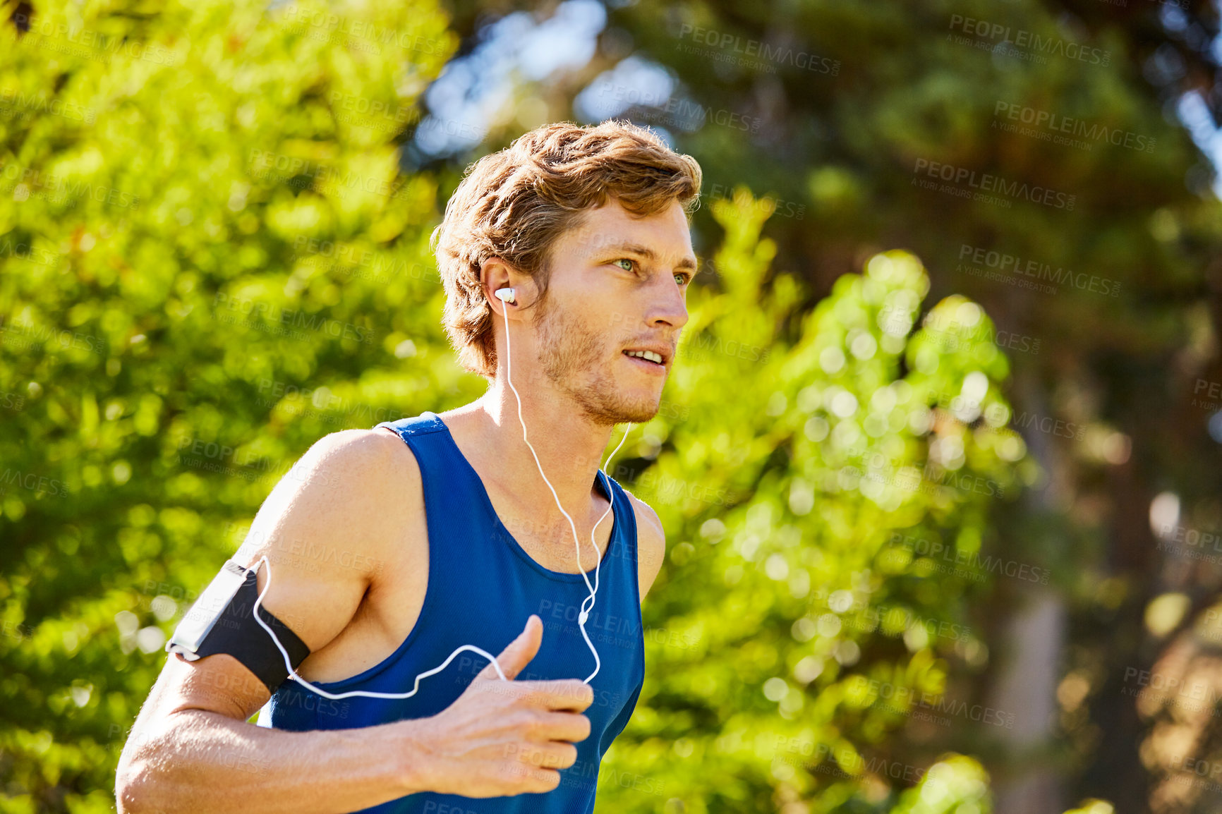 Buy stock photo Man, running and earphones in nature for cardio, fitness and streaming music with wellness exercise. Athlete, jogging and tech in park for radio, training tips podcast and serious for heart health