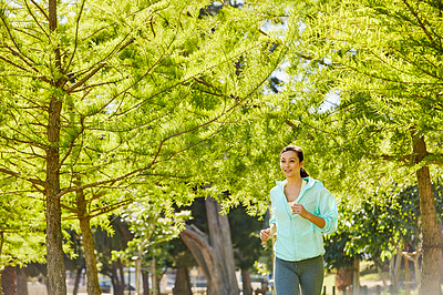 Buy stock photo Cropped shot of an attractive and athletic young sportswoman out for a jog in the park