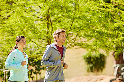 Buy stock photo Cropped shot of an affectionate and athletic young couple out for a jog in the park