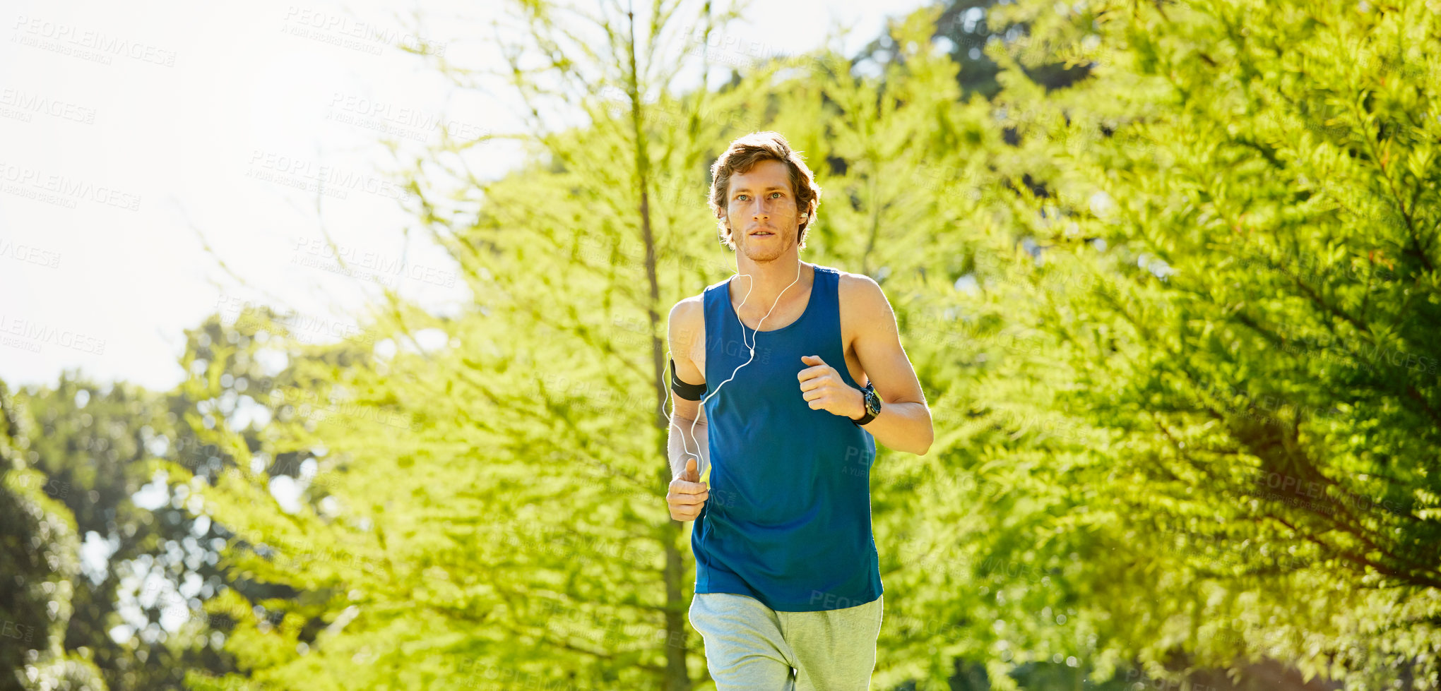 Buy stock photo Cropped shot of a handsome and athletic young sportsman listening to music while out for a jog in the park