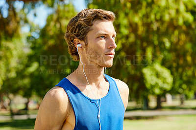 Buy stock photo Cropped shot of a handsome and athletic young sportsman out for a jog in the park