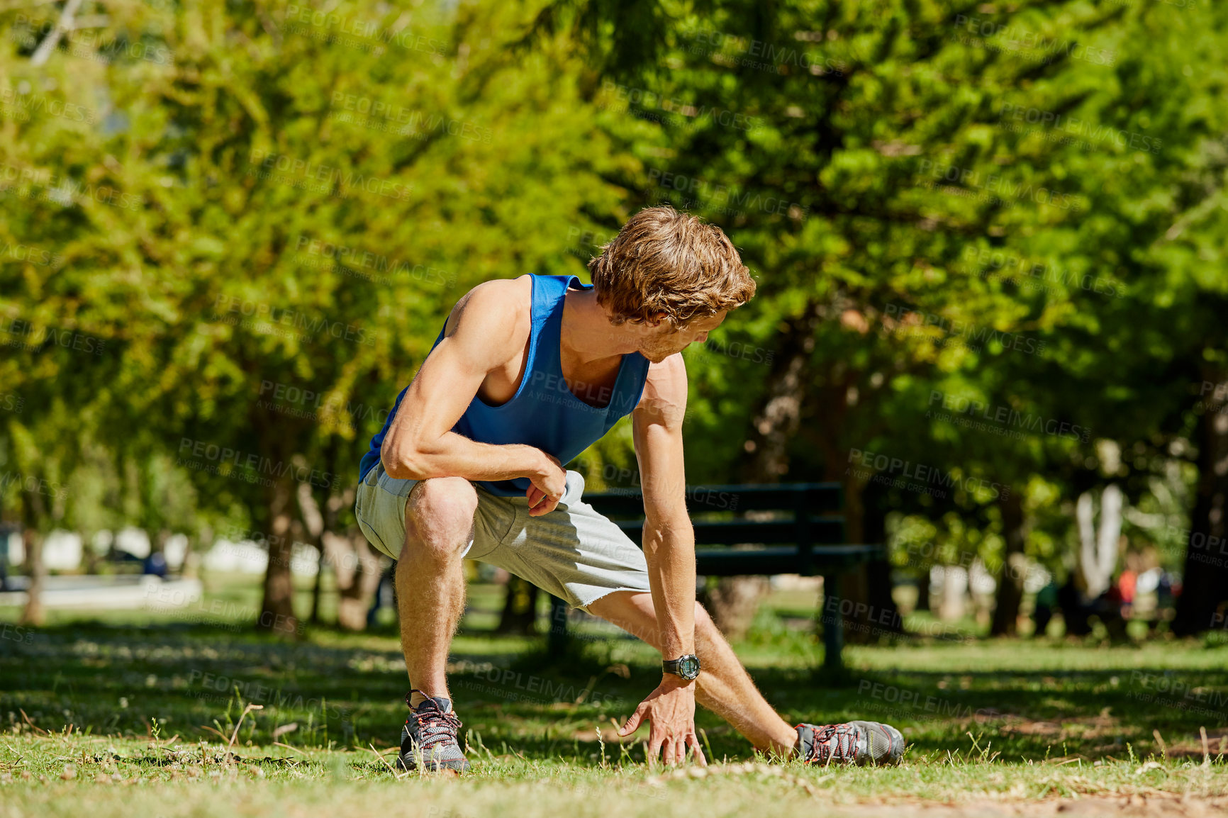 Buy stock photo Full length shot of a handsome and athletic young sportsman warming up before beginning his jog in the park