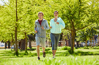 Buy stock photo Full length shot of an affectionate and athletic young couple out for a jog in the park