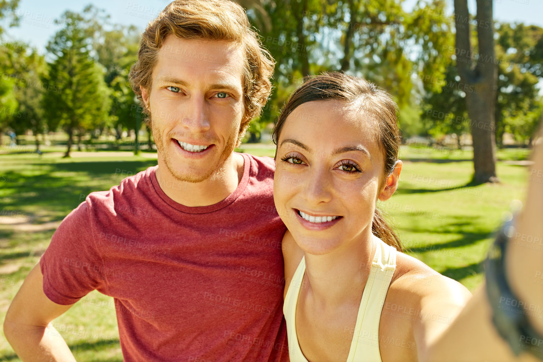 Buy stock photo Cropped portrait of an affectionate and athletic young couple taking selfies while out for a jog in the park