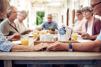 Buy stock photo Cropped shot of a group of senior citizens sitting together and holding hands to pray before enjoying their tea party