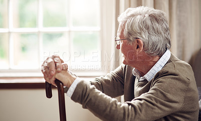Buy stock photo Shot of a senior man looking thoughtfully out of a window at home
