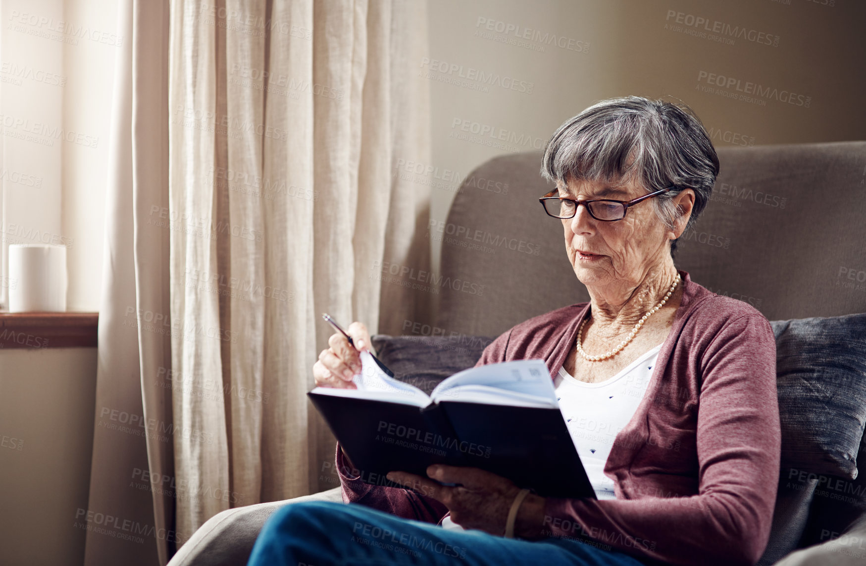 Buy stock photo Shot of a senior woman writing in a notebook at home