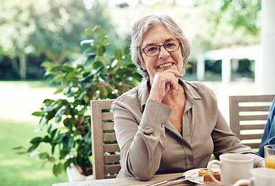 Buy stock photo Cropped portrait of a happy senior woman sitting with her hand on her chin during a tea party outdoors