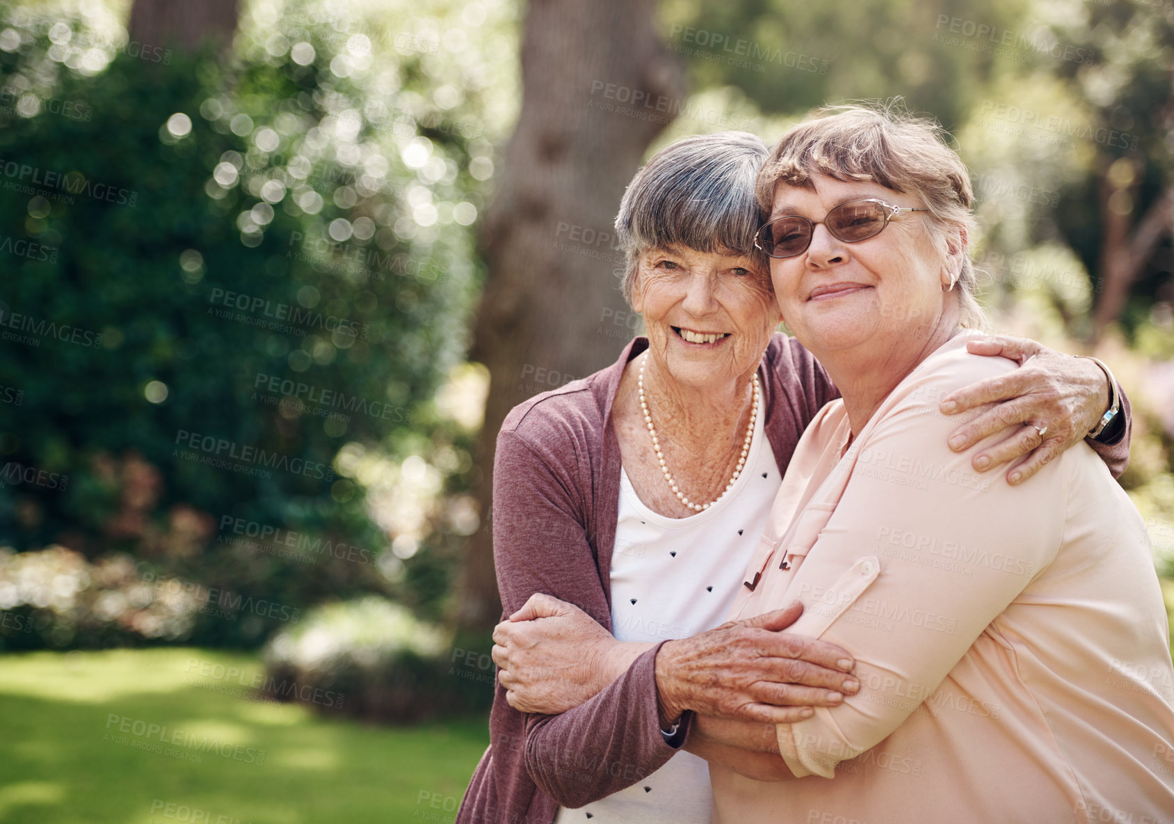 Buy stock photo Cropped portrait of two senior women holding each other during a day out in the garden