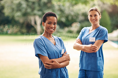 Buy stock photo Portrait of two confident young nurses standing outside in the garden of a retirement home