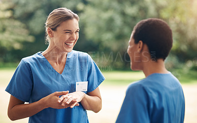 Buy stock photo Shot of two young nurses talking outside in the garden of a retirement home