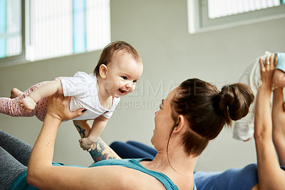 Buy stock photo Cropped shot of two attractive young mothers lying down and posing with her babies during a baby yoga class
