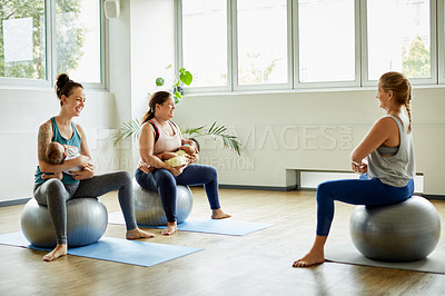 Buy stock photo Full length shot of two attractive young mothers sitting with their babies during a baby yoga class indoors