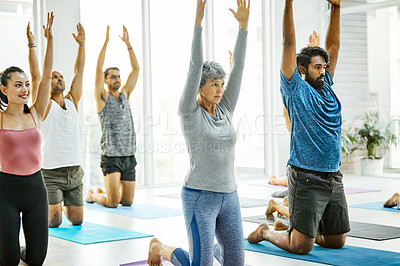 Buy stock photo Shot of a group of men and women practicing yoga in a fitness class