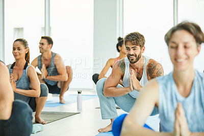 Buy stock photo Shot of a group of men and women practicing the garland pose during a yoga class